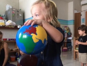 Niña explorando el globo terráqueo en el ambiente Montessori